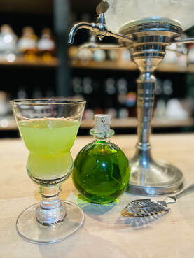 Absinthe glass with slotted spoon, louching fountain, and bottle of absinthe